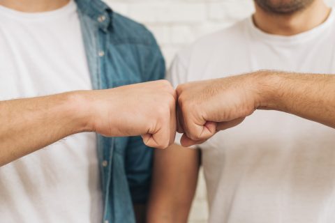 Un fist bump au dessus de deux écrans d'ordinateur portables